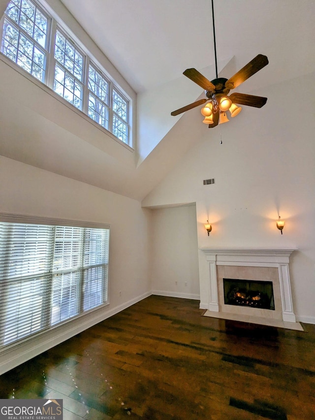 unfurnished living room with dark hardwood / wood-style floors, ceiling fan, and a towering ceiling