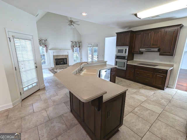 kitchen with a kitchen island with sink, sink, vaulted ceiling, appliances with stainless steel finishes, and plenty of natural light