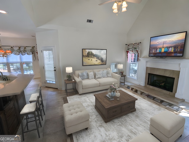 living room with a fireplace, light tile patterned floors, high vaulted ceiling, and ceiling fan