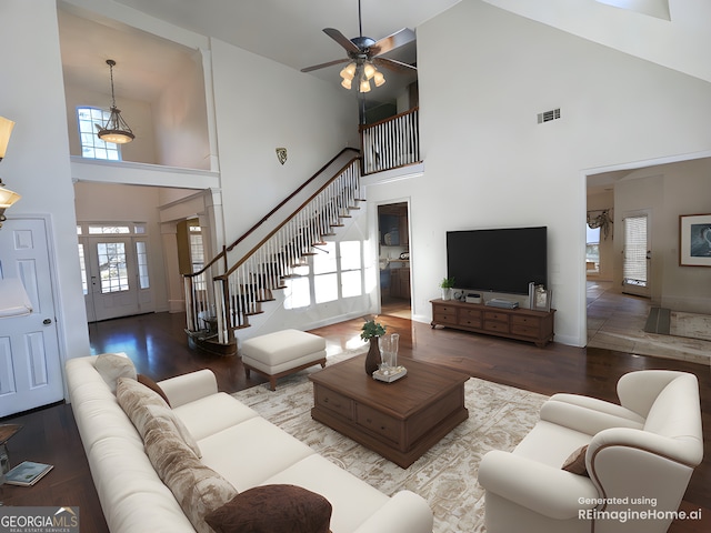 living room featuring wood-type flooring, a towering ceiling, and ceiling fan