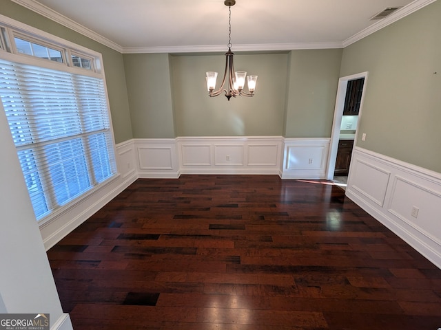 unfurnished dining area featuring dark hardwood / wood-style flooring, crown molding, and an inviting chandelier