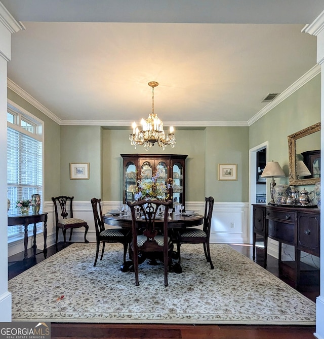 dining room with hardwood / wood-style flooring, ornamental molding, and an inviting chandelier