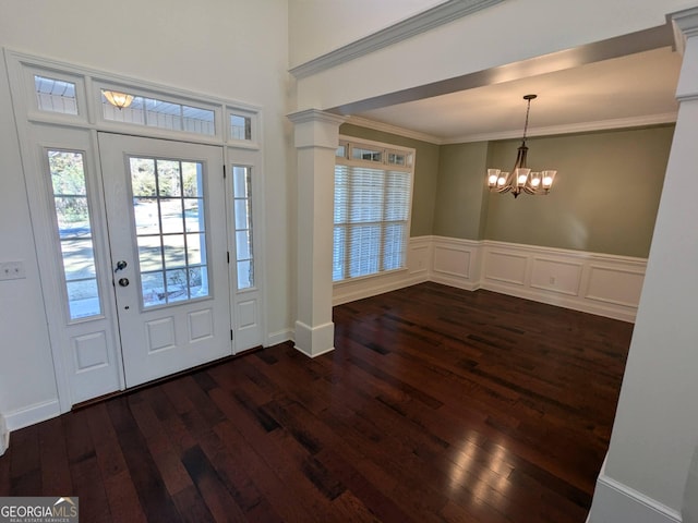 foyer with decorative columns, crown molding, dark hardwood / wood-style flooring, and an inviting chandelier