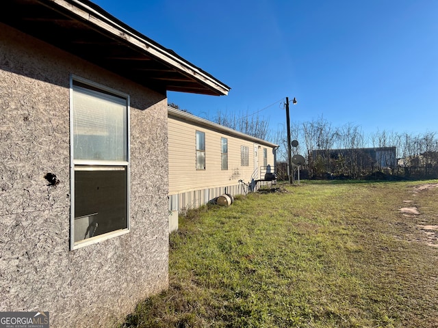 view of side of home with stucco siding and a lawn