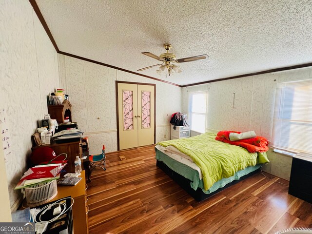 bedroom featuring ceiling fan, dark wood-type flooring, a textured ceiling, vaulted ceiling, and ornamental molding