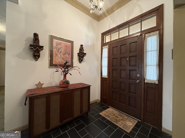 entrance foyer featuring a chandelier, dark tile patterned floors, and crown molding