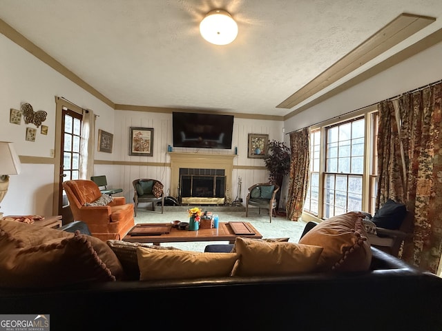 carpeted living room with a tile fireplace, crown molding, and a textured ceiling