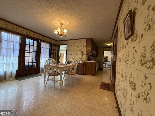 dining space with ornamental molding, a textured ceiling, and an inviting chandelier