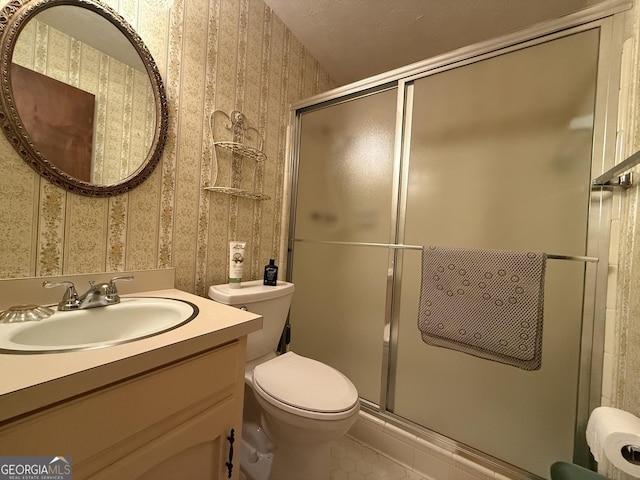 bathroom featuring toilet, vanity, tile patterned floors, and a shower with shower door