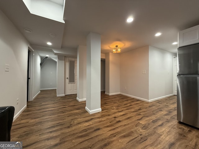 basement featuring stainless steel refrigerator and dark hardwood / wood-style floors