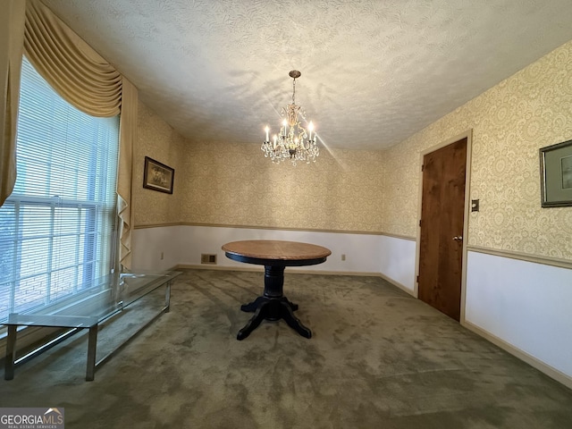 unfurnished dining area with carpet floors, a textured ceiling, and a chandelier