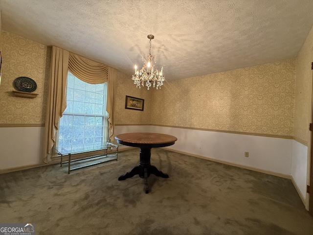 unfurnished dining area with carpet, a textured ceiling, and an inviting chandelier