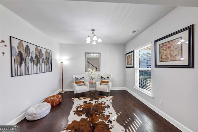 living area with baseboards, dark wood-style flooring, visible vents, and a notable chandelier