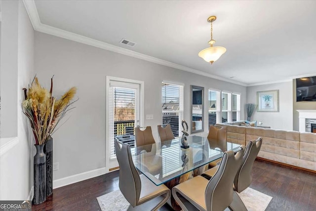 dining room featuring crown molding, a healthy amount of sunlight, and dark hardwood / wood-style floors