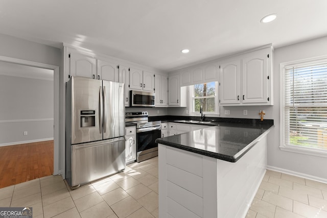 kitchen with white cabinetry, kitchen peninsula, stainless steel appliances, plenty of natural light, and light tile patterned flooring