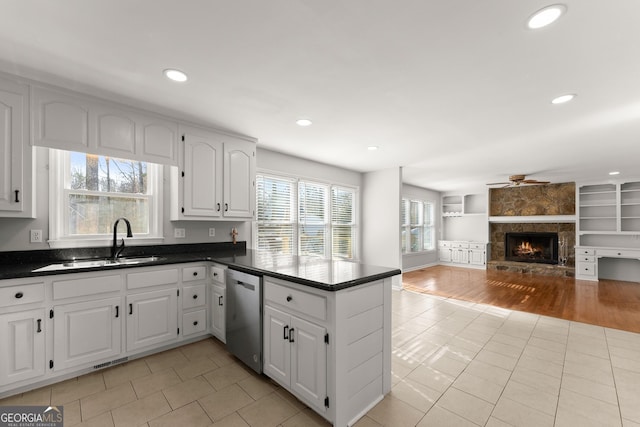 kitchen with dishwasher, kitchen peninsula, light tile patterned floors, built in features, and white cabinets