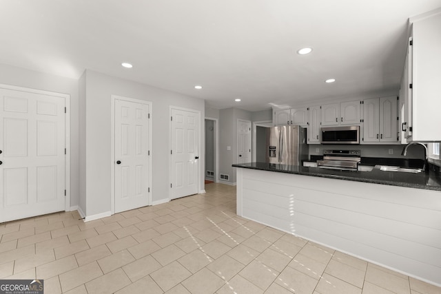 kitchen featuring kitchen peninsula, sink, light tile patterned flooring, stainless steel appliances, and white cabinets