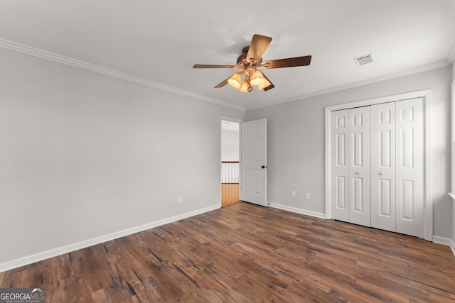 unfurnished bedroom with ceiling fan, a closet, dark wood-type flooring, and ornamental molding