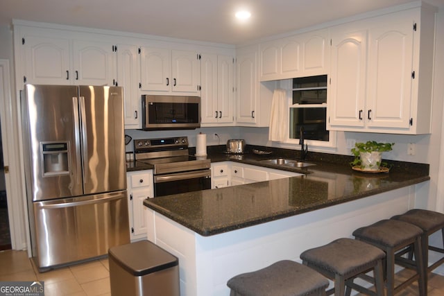 kitchen with kitchen peninsula, white cabinetry, sink, and stainless steel appliances