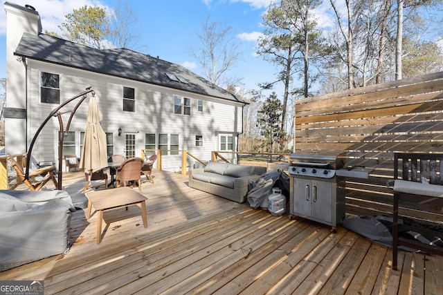 wooden deck with an outdoor hangout area and area for grilling