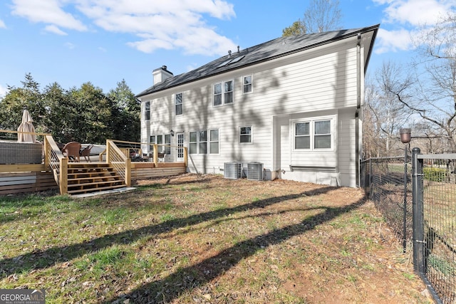 back of property with a deck, cooling unit, and a yard