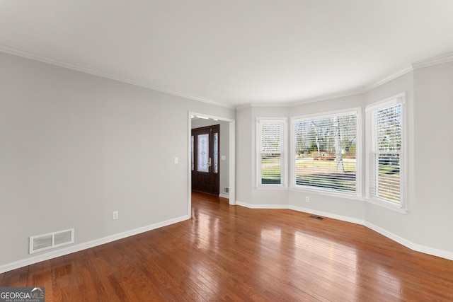 empty room featuring wood-type flooring and ornamental molding