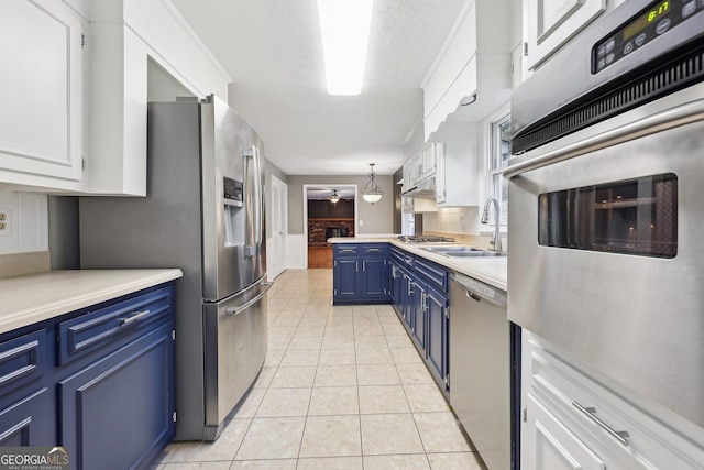 kitchen with blue cabinets, white cabinetry, sink, and appliances with stainless steel finishes