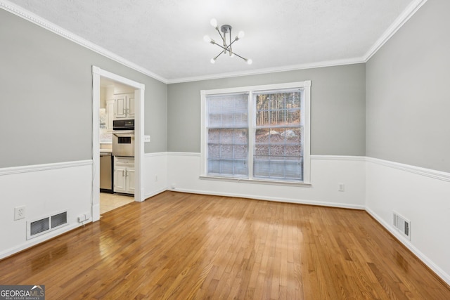 unfurnished dining area with light wood-type flooring, ornamental molding, and an inviting chandelier