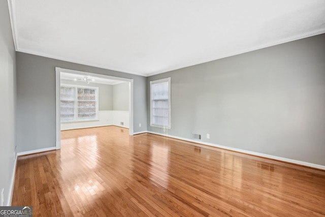 spare room featuring a notable chandelier, light hardwood / wood-style floors, and crown molding