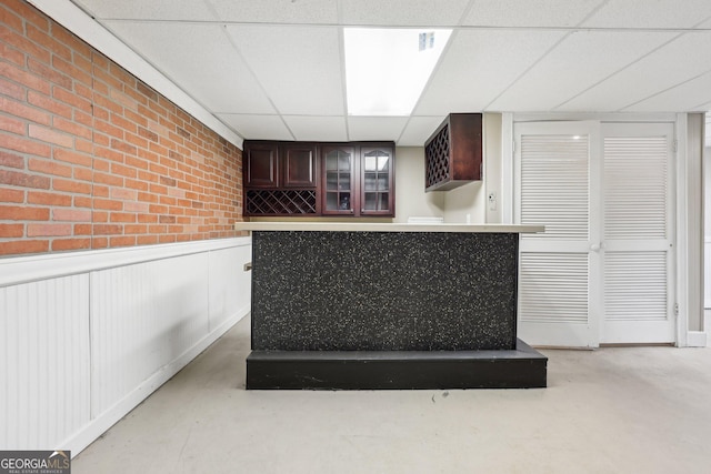 bar with a drop ceiling and dark brown cabinets