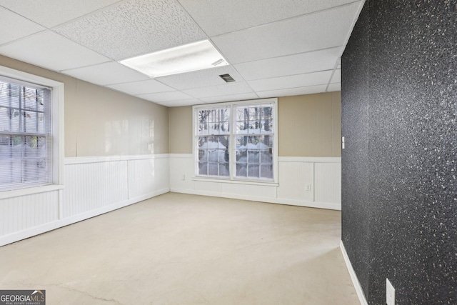 empty room with concrete flooring and a drop ceiling