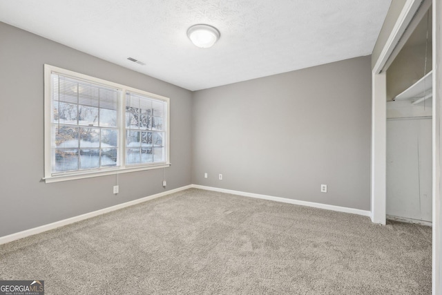 unfurnished bedroom featuring carpet flooring, a textured ceiling, and a closet