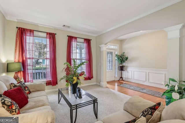 carpeted living room with decorative columns and crown molding