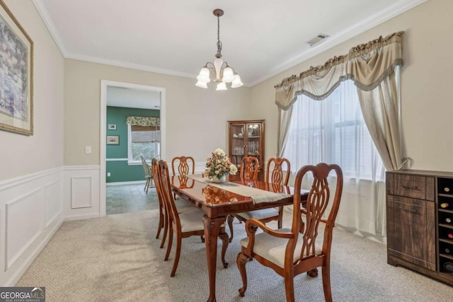 carpeted dining space with a chandelier and ornamental molding