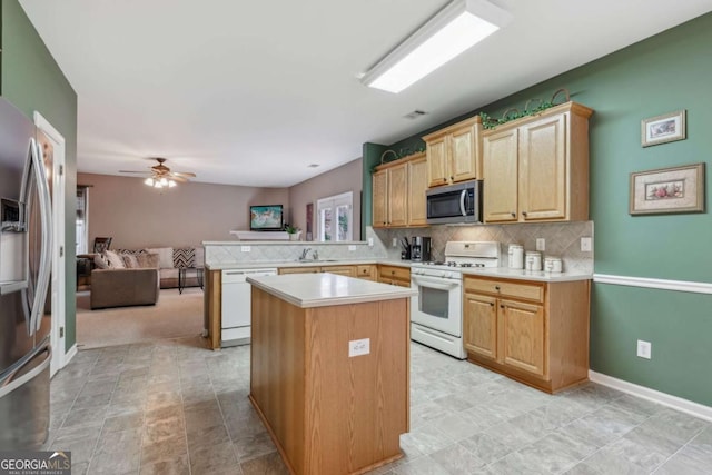 kitchen with kitchen peninsula, backsplash, stainless steel appliances, sink, and a center island