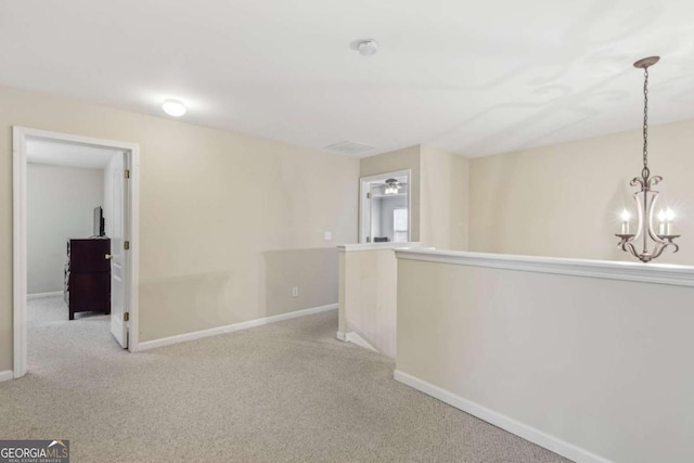 hall with light colored carpet and an inviting chandelier