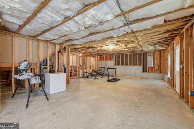 basement featuring electric panel and refrigerator