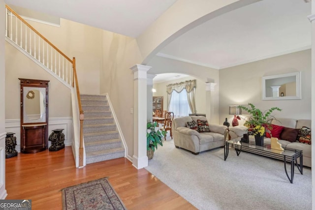 living room featuring wood-type flooring, ornate columns, and ornamental molding