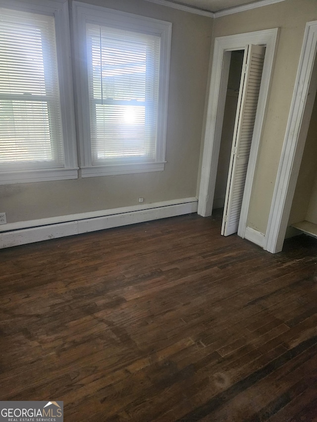 unfurnished bedroom featuring baseboard heating, crown molding, and dark hardwood / wood-style floors