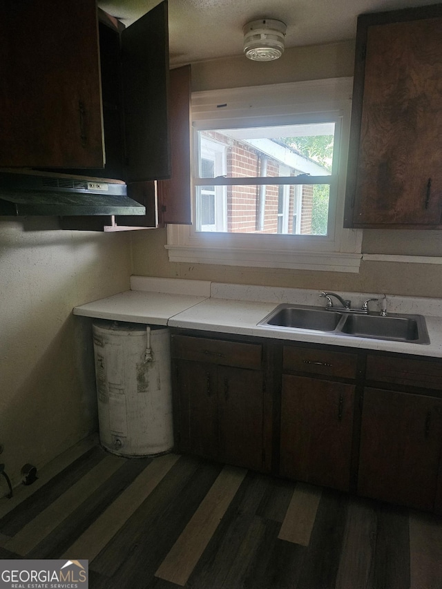 kitchen featuring dark brown cabinets, range hood, and sink