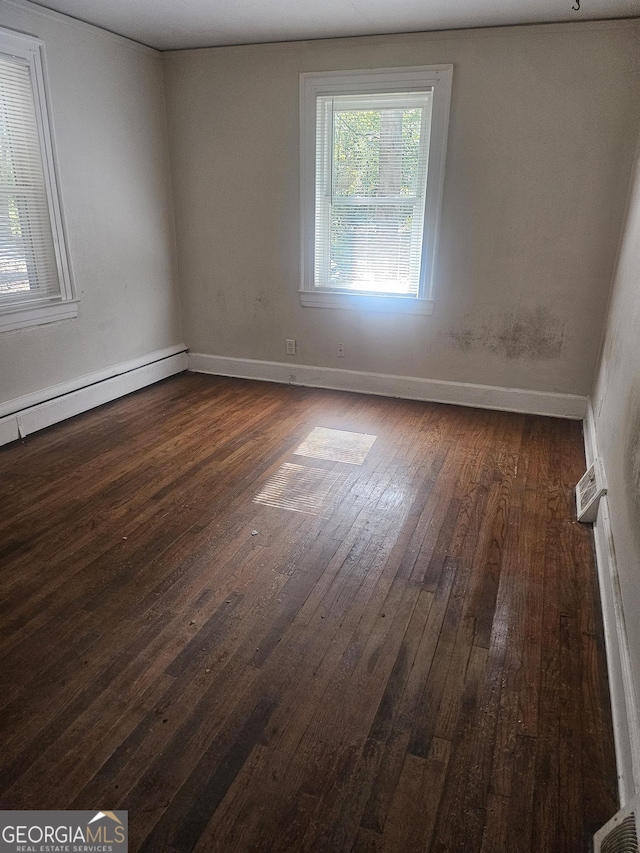 unfurnished room with dark wood-type flooring and a baseboard radiator