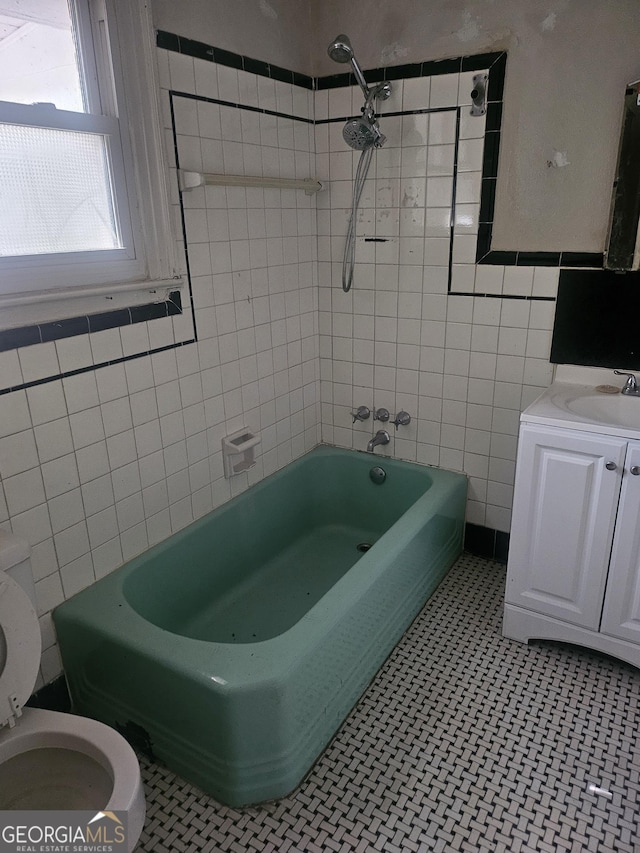 full bathroom with vanity, tiled shower / bath, tile patterned flooring, toilet, and tile walls