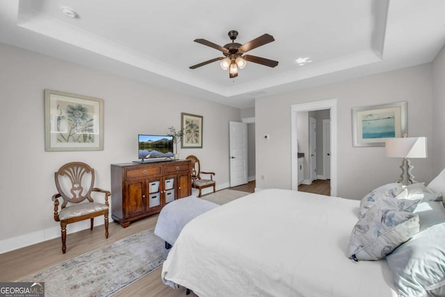 bedroom featuring light wood-type flooring, a raised ceiling, and ceiling fan