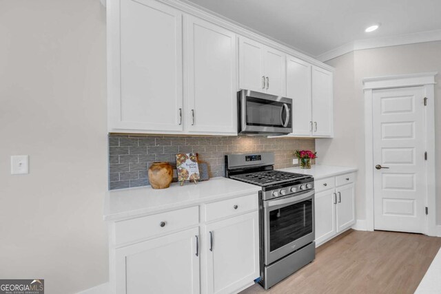 kitchen featuring light wood-type flooring, backsplash, stainless steel appliances, crown molding, and white cabinets