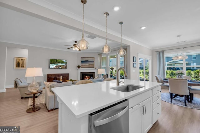 kitchen featuring sink, stainless steel dishwasher, decorative light fixtures, a kitchen island with sink, and white cabinets