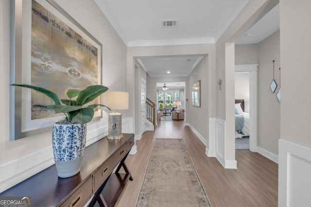 corridor featuring crown molding and light hardwood / wood-style flooring