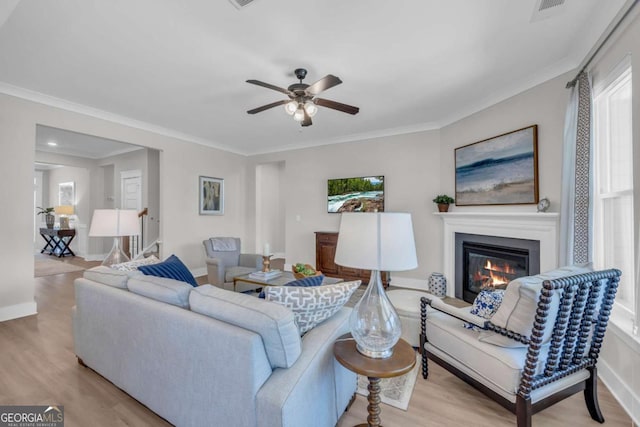 living room featuring ceiling fan, light wood-type flooring, and crown molding