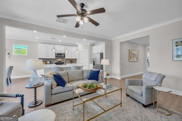 living room with light wood-type flooring, ceiling fan, and ornamental molding