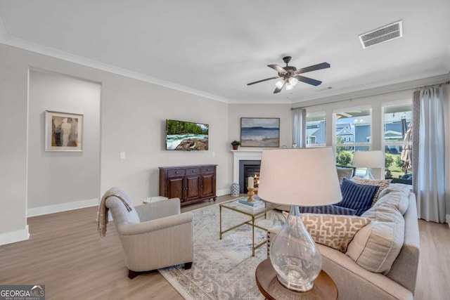 living room featuring ceiling fan, light hardwood / wood-style floors, and ornamental molding