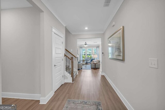 corridor with ornamental molding and light wood-type flooring